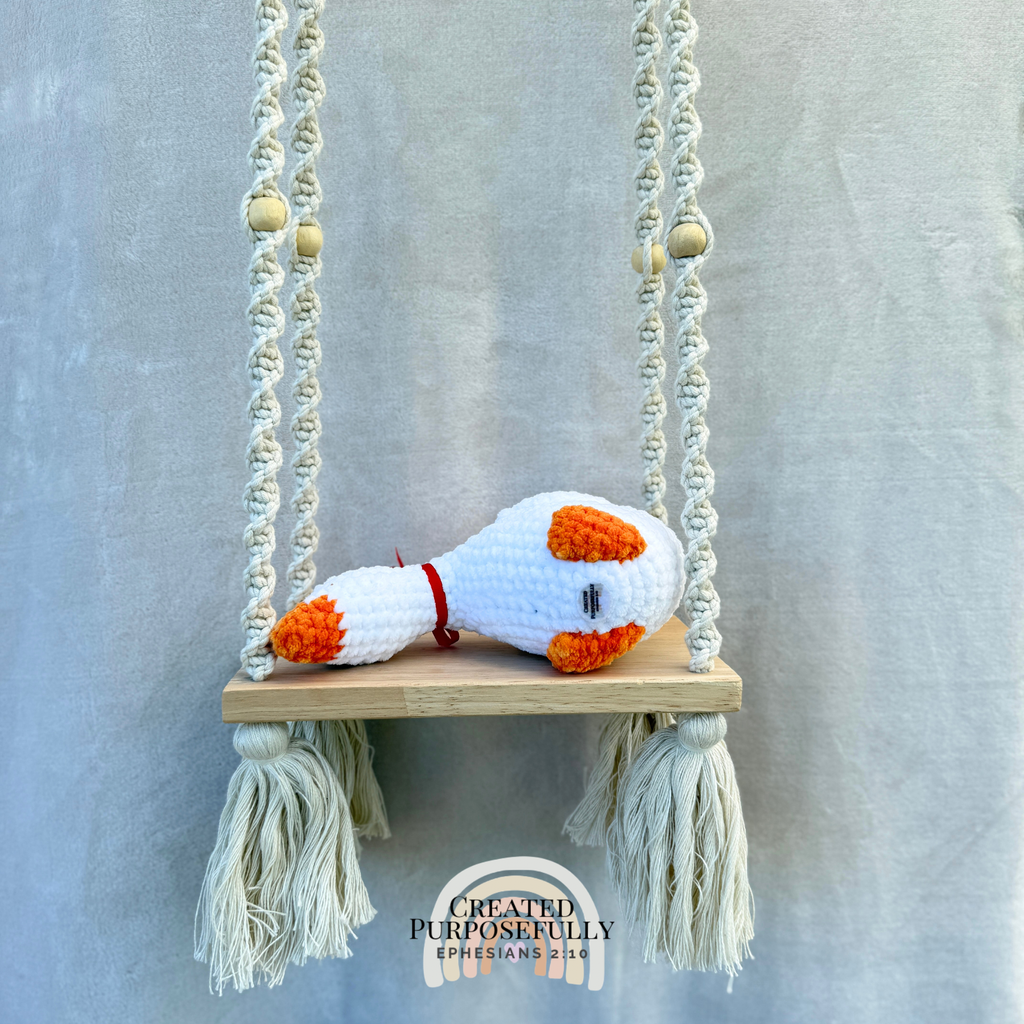 Handmade crochet shelf goose plush in a looking-down pose sitting on the edge of a shelf by Created Purposefully