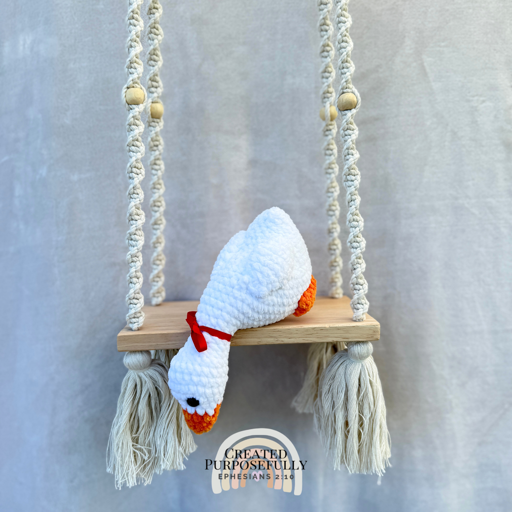 Handmade crochet shelf goose plush in a looking-down pose sitting on the edge of a shelf by Created Purposefully