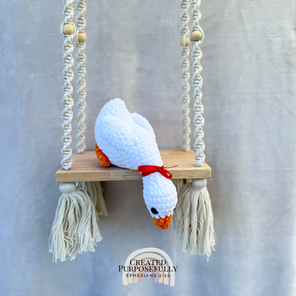 Handmade crochet shelf goose plush in a looking-down pose sitting on the edge of a shelf by Created Purposefully